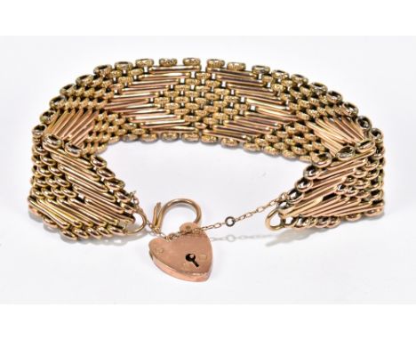 A yellow metal eleven bar gate link bracelet with 9ct gold heart shaped padlock clasp and safety chain, length 18cm, approx. 