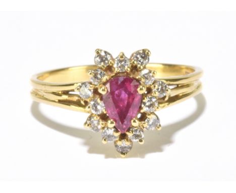 An 18ct yellow gold ruby and diamond cluster ring, the pear shaped ruby within a border of fourteen brilliant cut diamonds, s