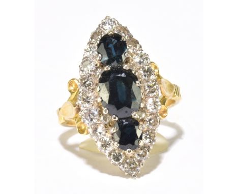 A yellow metal sapphire and diamond marquise shaped cluster ring, set with three oval mixed cut sapphires bordered by twenty 