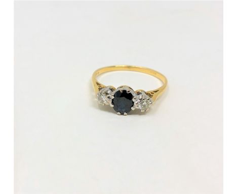 An 18ct gold sapphire and diamond three stone ring, the oval sapphire weighing an estimated 0.70 carat, the total diamond wei