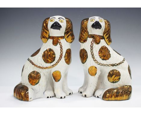 A pair of Staffordshire pottery spaniels, late 19th century, with separately moulded front legs and copper patch details, hei