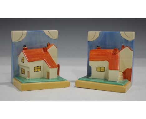 A pair of Clarice Cliff Wilkinson pottery Cottage bookends, shape No. 410, the orange roofed houses on green and yellow stepp