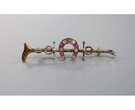 A late Victorian yellow metal, ruby and diamond set horseshoe and riding crop bar brooch, 50mm, gross weight 5.4 grams.