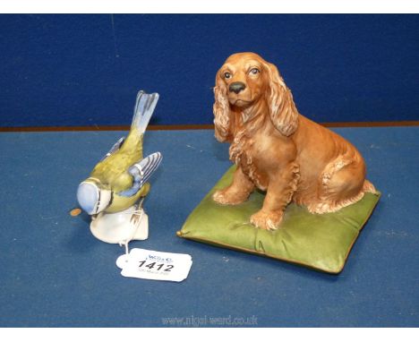 A Goebel model of a blue tit, 3 1/2'' high plus a Naples model of a Spaniel sitting on a green cushion, 5'' high (a/f)