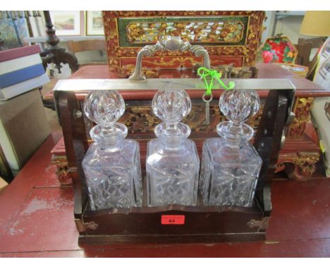 A mahogany Tantalus with silver plated mount and handle with three cut glass whisky decanters and stoppers (with key) 