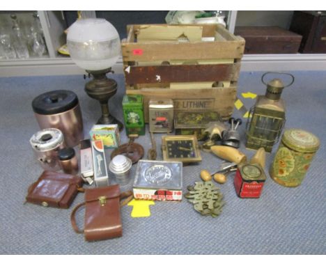A Henniez Lithinet wooden crate containing a mixed lot to include vintage tins, two cameras, oil lamp and shade and other ite