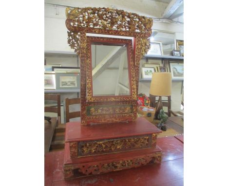 A 19th/20th century Chinese red lacquered table top mirror, carved and pierced with birds, flowers and foliage, highlighted i