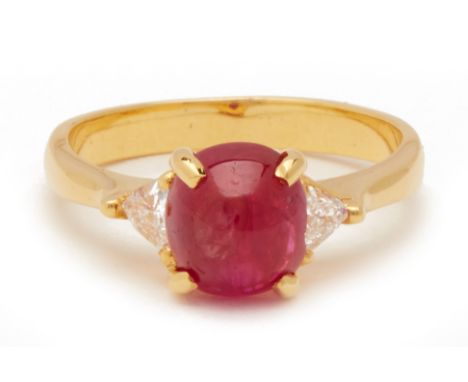 A RUBY AND DIAMOND RING Set in 20k yellow gold, the cabochon cut ruby flanked by trilliant cut diamonds The ruby weighing app