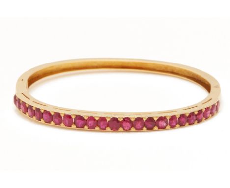 AN UNTREATED RUBY BANGLE
The yellow gold hinged bangle set with 23 round and oval cut rubies
The rubies totalling approximate
