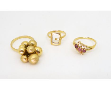 Three 18ct gold rings, a buckle ring, size H1/2, bobbles ring, size O1/2, and a ruby and diamond accent ring, weight all toge