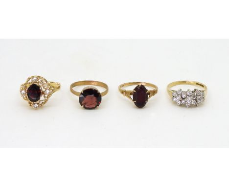 A 9ct gold clear gem set cluster ring, size O, together with three 9ct and yellow metal garnet rings, a round solitaire size 