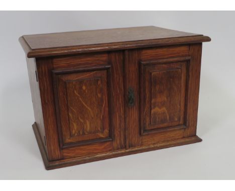 A late 19th/early 20th Century oak canteen of cutlery, the pair of panelled doors enclosing three fitted drawers containg mot