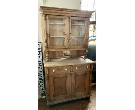 A Victorian pine chiffonier bookcase, moulded cornice above two panel glazed door bookcase, enclosing three shelves, on a mou