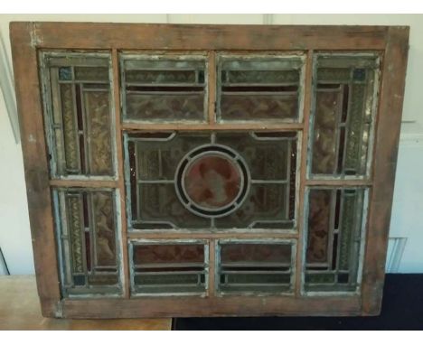 A stained and leaded glass window, the panels of scrolling design centred by a female portrait roundel, mounted in wood frame