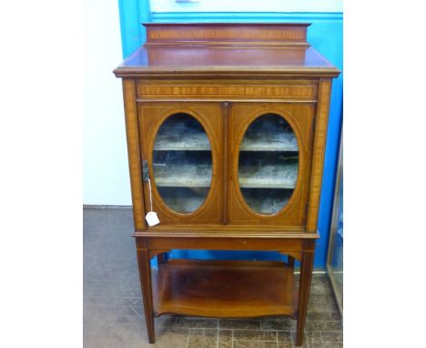 An Antique Mahogany Music Cabinet, oval glazed fronted door, the cabinet has three internal shelves and a shelf beneath, with