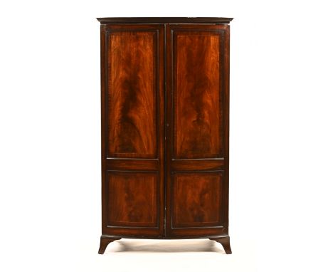 An Edwardian inlaid mahogany George III style bowfronted wardrobe, the boxwood and ebony strung doors opening to an interior 