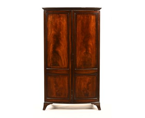 An Edwardian inlaid mahogany George III style bowfronted wardrobe, the boxwood and ebony strung doors opening to an interior 