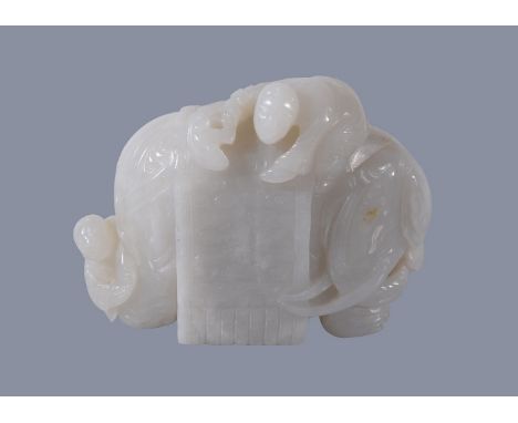 A Chinese white jade carving of and elephant, with brown inclusion to one side, with one figure on the elephants back holding