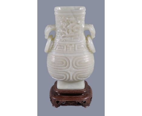 A Chinese white jade vase, hu, the pear-shaped vessel quartered on each side by high strapwork into four panels of rounded re