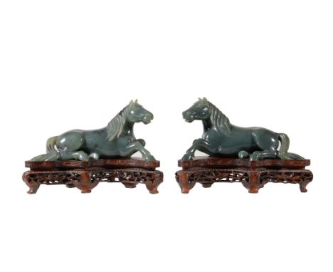 A pair of Chinese spinach jade models of recumbent horses, facing to the left and right, with carved details, circa mid-20th 