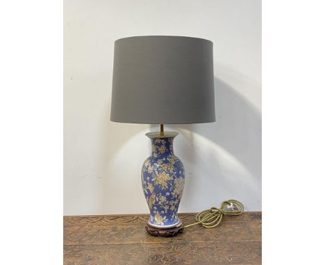 A Chinese style ceramic baluster lamp, enamelled with lotus heads and birds, on a hardwood base H64cm