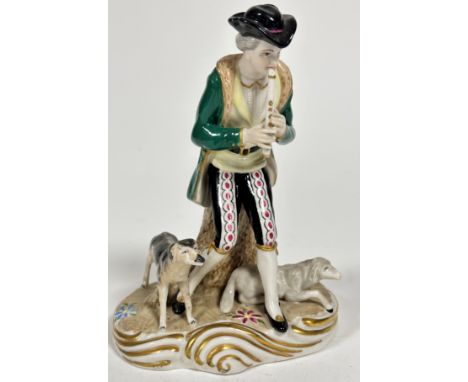 A Continental porcelain figure of a Shepherd playing a flute with seated sheep and standing sheepdog, decorated with polychro