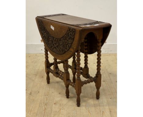 An early 20th century oak gate leg drop leaf table, the carved circular top over bobbin turned supports, H66cm, D73cm