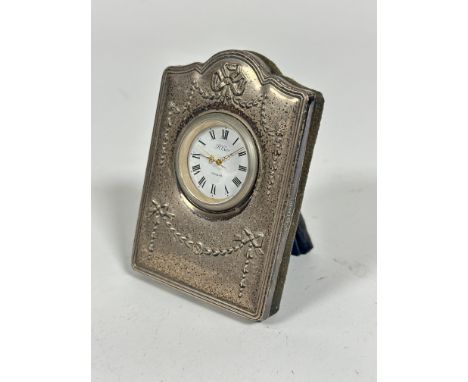 A modern R Carr quartz movement bedside clock with modern silver mounted chased frame, with plush back on easel stand, (9cm x