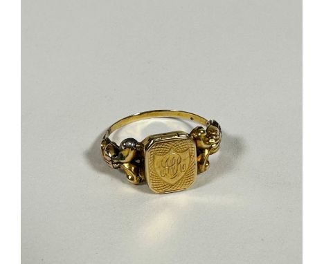 A 19thc yellow metal ring, the centre panel with shield shape design with engraved initials A C R, with lift-up panel a/f, on