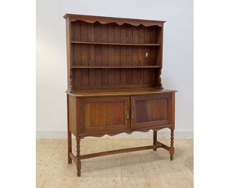 An early 20th century oak dresser, with two height plate rack over twin panelled cupboard doors to base, raised on bobbin tur