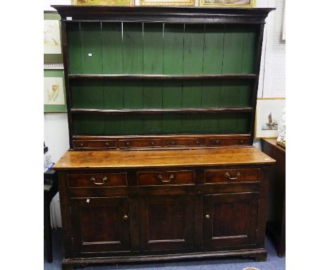 A George III oak and elm Dresser, the dentil cornice above shelves, small drawers and an enclosed back; the base with four sh