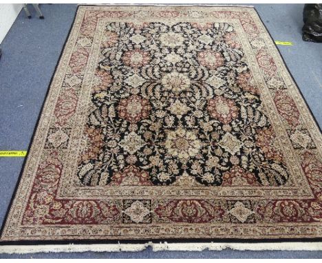 A large hand-knotted Persian-style wool Rug, black ground with dark rust and light gold stylized geometric patterns, made by 