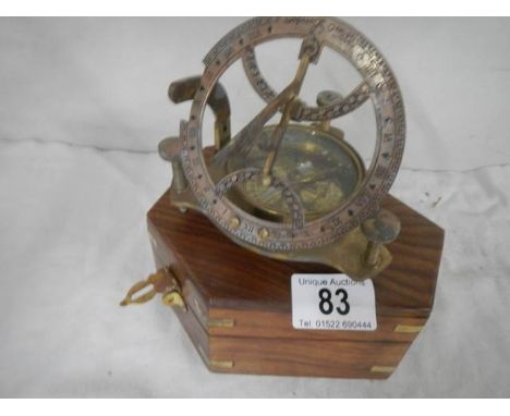 A brass compass / sundial in a teak box.