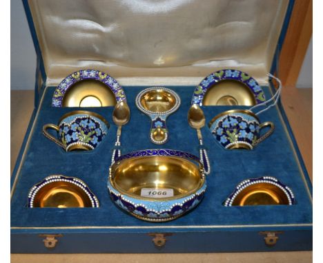 A Russian silver gilt and enamel tea for two, comprising teacups and saucers, teaspoons, shaped side dishes, tea strainer and