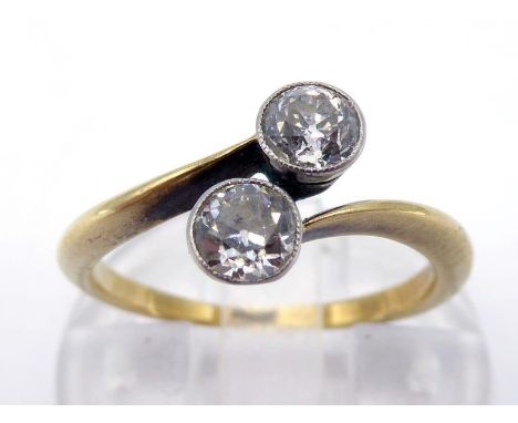 A two stone diamond ring, circa 1920, the two millgrain set old European cuts totalling approx. 0.44 carat, obliquely set, to