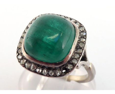 An emerald and diamond ring, the large square cushion cabochon emerald 11.3 x 10.7mm, in a surround of small rose cuts, mount