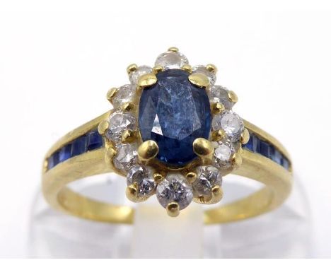 A sapphire and diamond cluster ring, the central oval cut sapphire 6 x 4mm, in a surround of small brilliants, to channel set