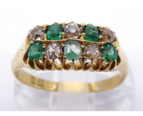 A 1930s 18 carat gold, emerald and diamond ring, composed of a checker board bezel of small round cut emeralds and old brilli