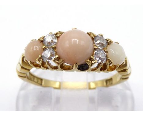 A Victorian peau d'ange coral and diamond half hoop ring, the three graduated oval coral cabochon with pairs of old mine cut 
