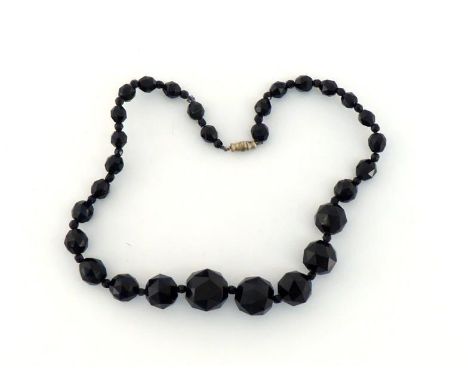 A jet bead necklace, composed of graduated circular facetted beads, to a screw barrel clasp, 43cm long, together with a nephr
