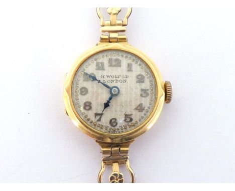 A lady’s 18 carat gold manual wind wristwatch, retailed by Herbert Wolf, with silvered engine turned dial, signed ‘H.WOLF’, w