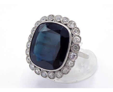 A French platinum, sapphire and diamond cluster ring, the large shallow sapphire approx. 11.68 carats, in a millgrain set sur