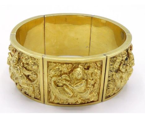 An Indian yellow metal (tests 14 carat gold) bangle, each link embossed with a Buddhist deity, to a concealed clasp, 6.2cm in