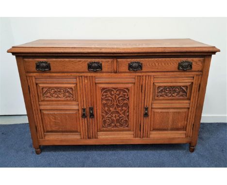 EDWARDIAN LIGHT OAK SIDEBOARDwith a moulded top above two panelled frieze drawers with three carved panelled cupboard doors b