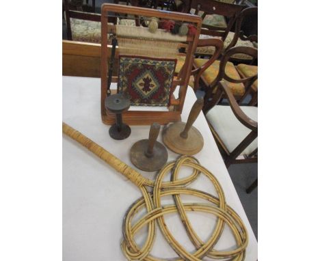 A needlepoint work frame enclosing a woollen carpet sample, together with three vintage treen spools and a carpet beater 