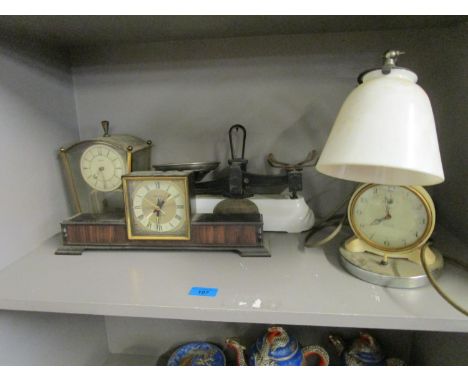 A group of clocks to include one mounted on a table lamp with adjustable white glass shade, along with Pooley &amp; Son kitch