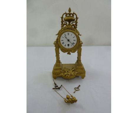 A 19th century French gilded metal mantle clock of architectural form, enamel dial with Roman numerals, to include key and pe