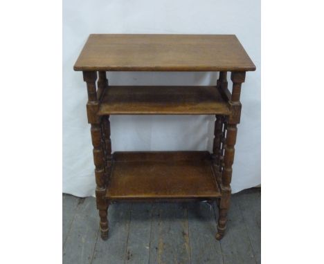 An oak Continental library bench with two shelves on turned legs with wooden castors