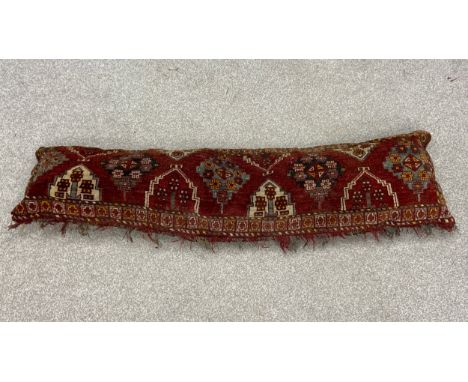 A 20th century draft excluder or large cushion handmade from a piece of carpet with a patterned needlework back. L.180. W.49c