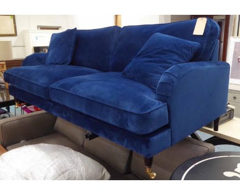 SOFA, Howard style, in midnight ink blue velvet upholstery with two scatter cushions on turned legs with front brass castors,